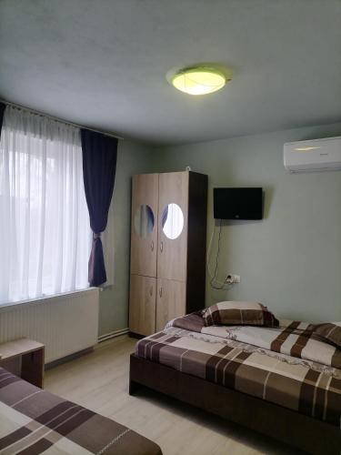 a bedroom with two beds and a cabinet and a television at Pensiunea Melissa in Măceşu de Jos