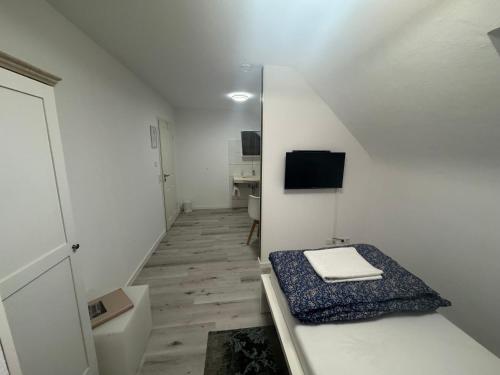 a small white room with a bed and a television at Dasluki in Köngen
