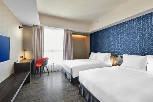 a hotel room with two beds and a television at Holiday Inn Express Kaohsiung Love River by IHG in Kaohsiung