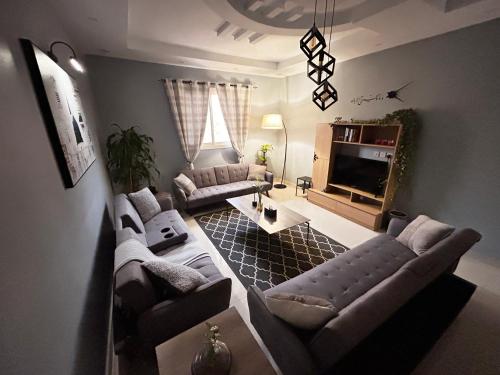 a living room with two couches and a tv at HOMEY iNN in Al Madinah