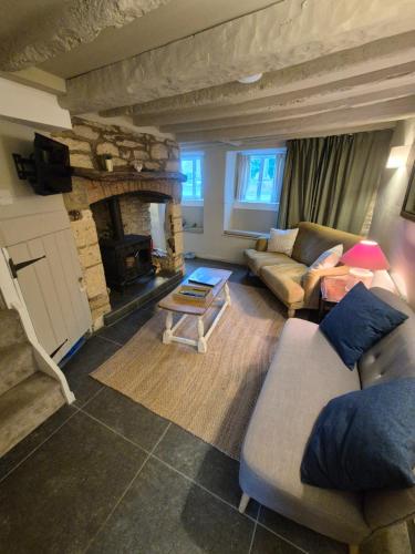 a living room with a couch and a fireplace at Cosy Cotswold Cottage in Stow on the Wold