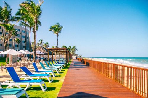 a boardwalk leading to the beach with chairs and umbrellas at Costeira Palace Beach Resort All Inclusive in Natal