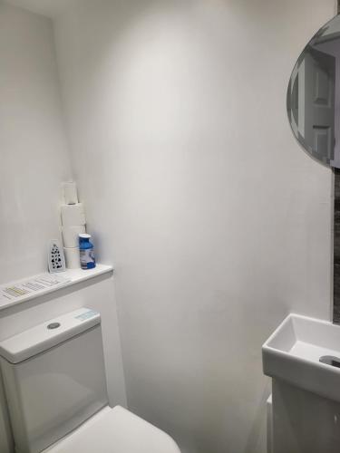 a white bathroom with a toilet and a sink at Evabrite Homes in Dartford
