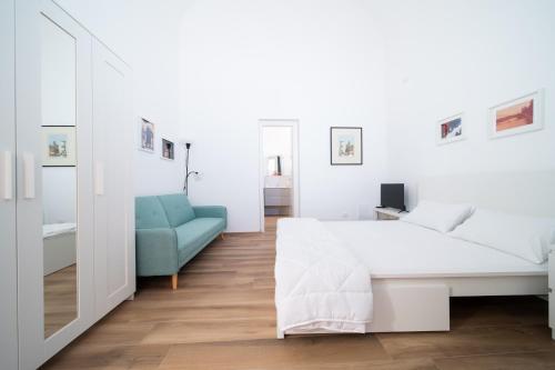 a bedroom with a white bed and a blue chair at La dimora di via Umberto-private bathrooms in Catania