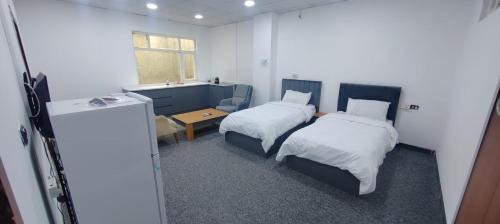Motel beyza في السليمانية: غرفة صغيرة بسريرين وطاولة