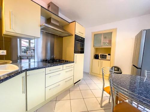 une cuisine avec des placards blancs, une table et un comptoir dans l'établissement Meygal Color - WiFi - 3 étoiles - 20min du Puy, à Lantriac