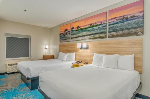 a hotel room with two beds and a desk at Days Inn & Suites by Wyndham Prattville-Montgomery in Prattville