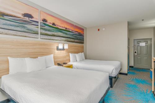 a hotel room with two beds and a painting on the wall at Days Inn & Suites by Wyndham Prattville-Montgomery in Prattville
