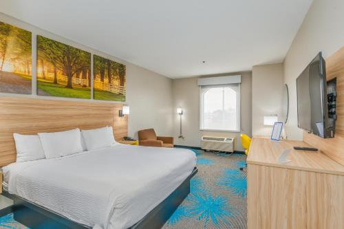 a hotel room with a bed and a flat screen tv at Days Inn & Suites by Wyndham Prattville-Montgomery in Prattville