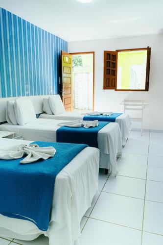 a room with four beds with blue and white sheets at Pousada Ouriço in Porto De Galinhas