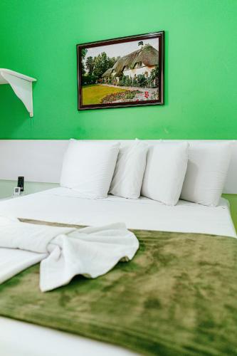 a white bed with white pillows and a green wall at Pousada Ouriço in Porto De Galinhas
