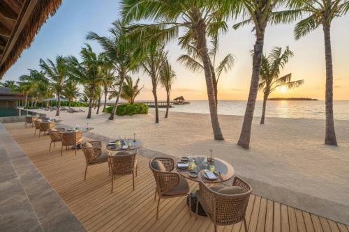 a restaurant on the beach with palm trees at JW Marriott Maldives Kaafu Atoll Island Resort in Male City