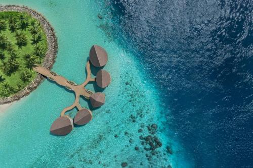 an island with a tree in the middle of the ocean at JW Marriott Maldives Kaafu Atoll Island Resort in Male City