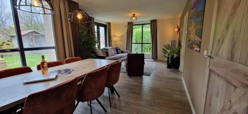 a living room with a large wooden table and chairs at Gezellig 6pers Familiehuis grote tuin met BBQ aan meer Gelderland in Ewijk