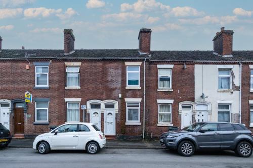 two cars parked in front of a brick building at 2Bed Mid Terrace Close To Station in Stoke on Trent
