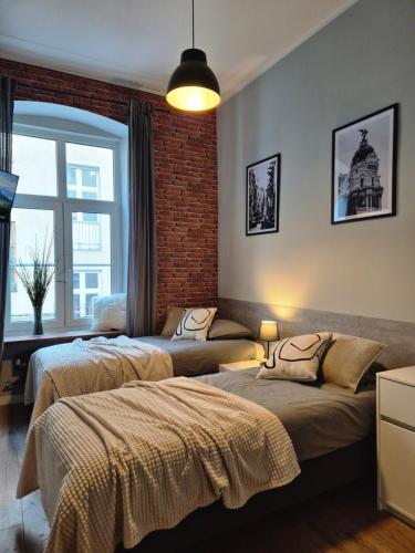 a bedroom with two beds and a brick wall at Five Rooms Piotrkowska 28 in Łódź