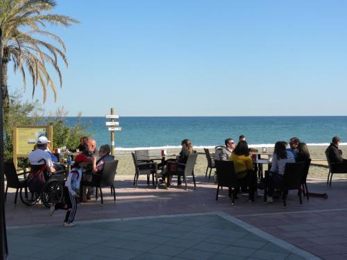 a group of people sitting at tables on the beach at Don Agustin in San Luis de Sabinillas