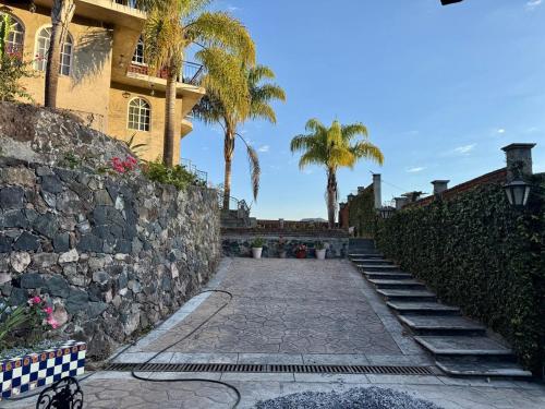 a stone walkway leading to a building with palm trees at Casa del Lago in Nuevo San Juan Parangaricutiro