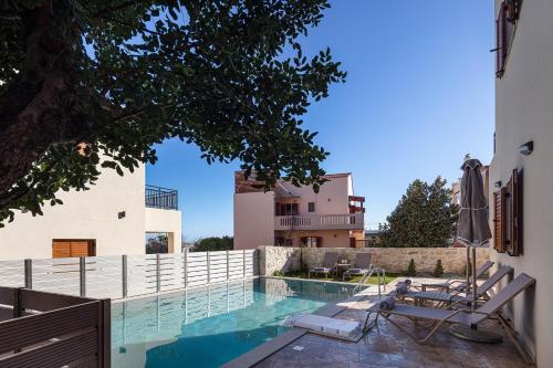AtsipopouloにあるPROVILLAS - Ι, ΙΙ & ΙΙΙ - Luxury Villas with private pool near Retrymnoの椅子と家のあるプール