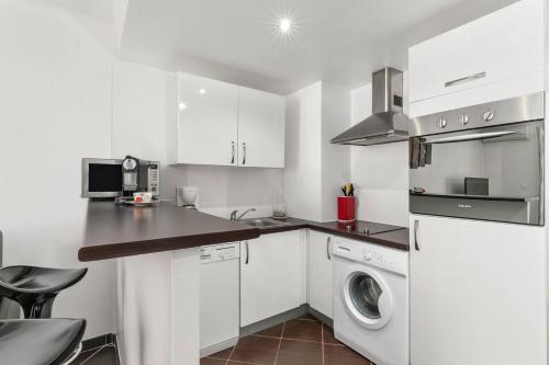 une cuisine avec des armoires blanches et une laveuse et une sécheuse dans l'établissement Luxury Studio YourHostHelper, à Cannes