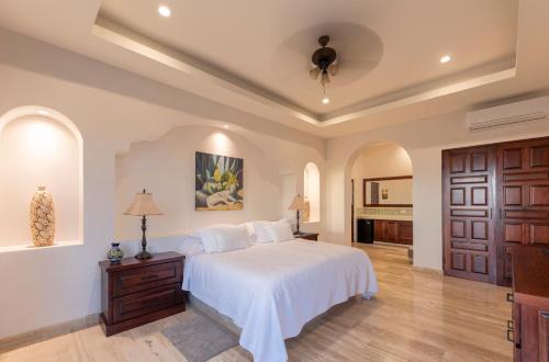 a bedroom with a white bed and a wooden door at Hacienda Todos Los Santos in Todos Santos