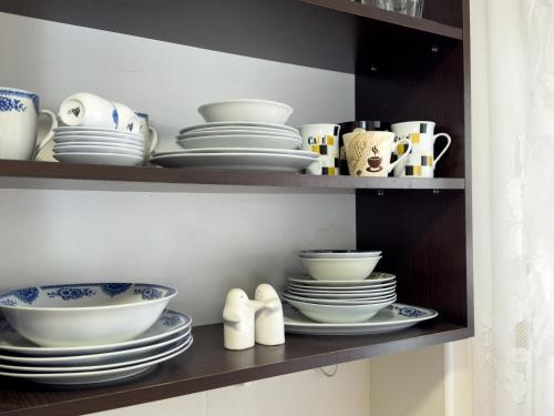 a shelf filled with plates and cups and bowls at Cosy two-bedroom apartment in Becici by sea and mountains in Becici