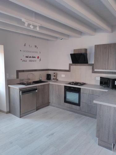 a kitchen with stainless steel appliances and wooden cabinets at L 'échappe-loups maison de 2 à 8 personnes et garage in Chapelle-Agnon