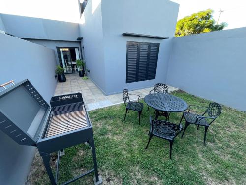 a barbecue grill with chairs and a table on a yard at Duplex LM in Chivilcoy