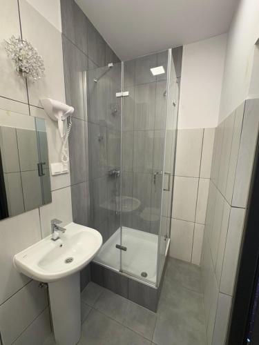 a bathroom with a glass shower and a sink at Hotelik & Restauracja Amber in Raszyn
