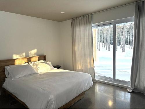 une chambre avec un lit et une grande fenêtre dans l'établissement Cottage Quebec - L'Eclipse Nordique, à Petite-Rivière-Saint-François