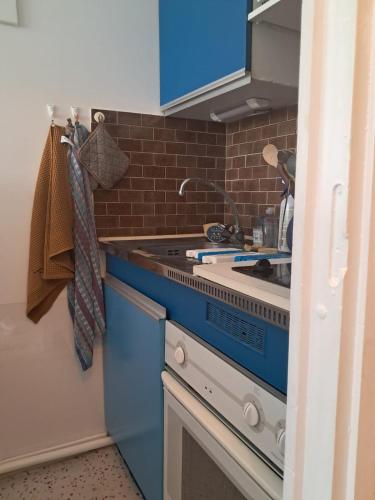 - une cuisine bleue avec évier et cuisinière dans l'établissement Appartement à 1 minute de la mer, à La Grande Motte