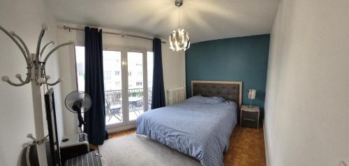 una camera da letto con un letto e una grande finestra di Appart à Maisons Alfort en plein centre ville à 5 min de la Gare Rer a Maisons-Alfort