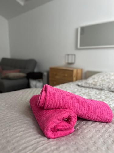 - une serviette rose assise au-dessus du lit dans l'établissement le nid de Mymy, à Nuits-Saint-Georges