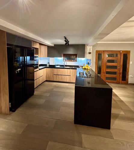 a large kitchen with a black island in a room at LP Finca la Pergola, Naturaleza con Lujo y una increíble vista a todo Medellín in Medellín