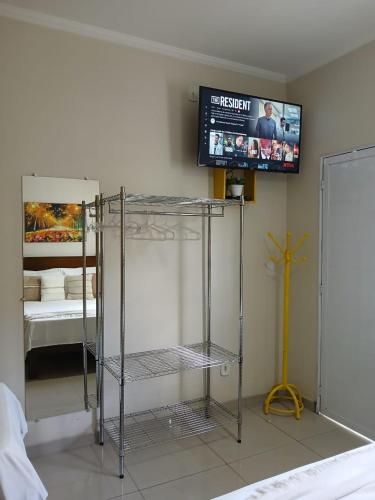 a room with a tv on the wall next to a bed at Hospedagem Quarto Chic centro Cunha in Cunha