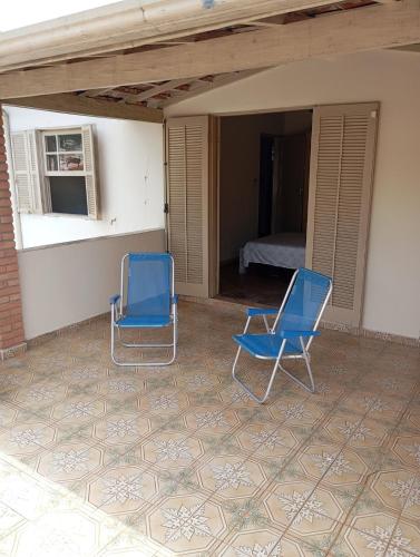 two blue chairs sitting on a patio with a bedroom at Casa em Aparecida SP in Aparecida