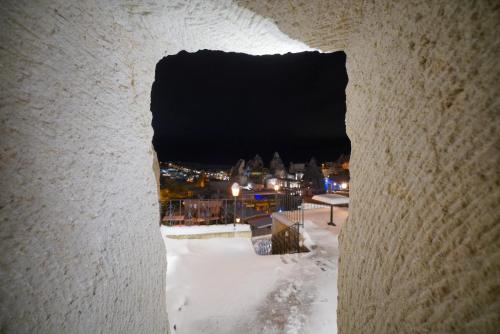 a view through a hole in a wall with snow at Asteria Cave Hotel in Goreme