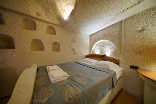 a small bedroom with a bed in a stone wall at Asteria Cave Hotel in Goreme