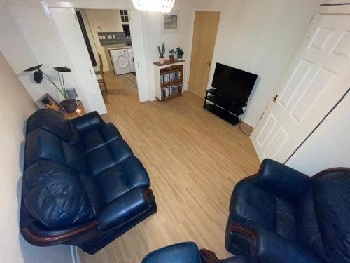a living room with a leather couch and a television at John Lennon Airport house in Liverpool
