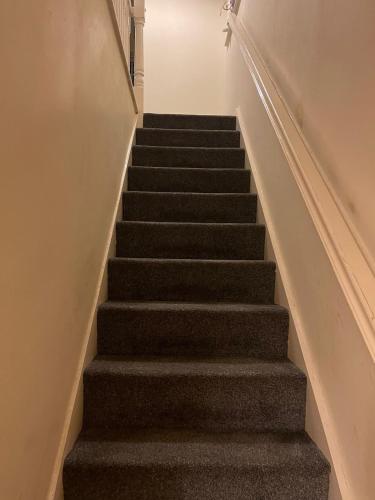 a staircase with grey carpeting and a stair case at John Lennon Airport house in Liverpool