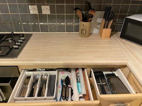 a kitchen counter with a drawer filled with utensils at John Lennon Airport house in Liverpool