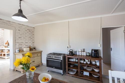 a kitchen with a stove and a table with yellow flowers at Tevrede in Middelplaas