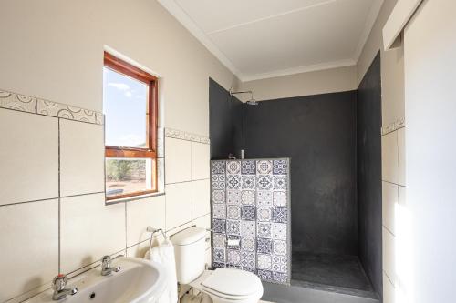 a bathroom with a toilet and a sink and a shower at Tevrede in Middelplaas