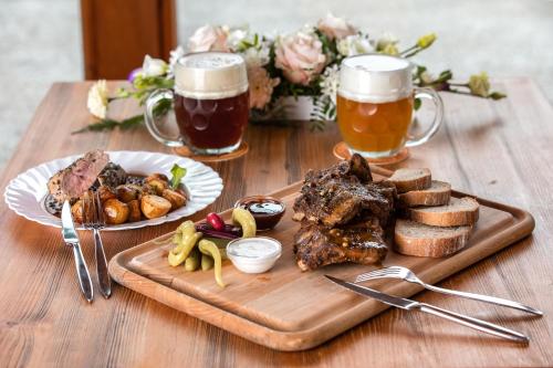 a wooden table with a plate of food and two glasses of beer at Wellness hotel & minipivovar Kněžínek in České Budějovice