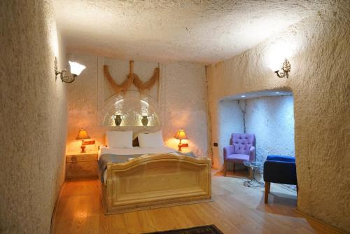 a bedroom with a bed and a blue chair at Asteria Cave Hotel in Goreme