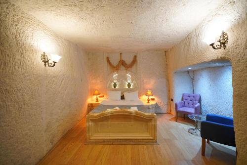 a bedroom with a bed and a purple chair at Asteria Cave Hotel in Goreme