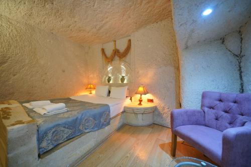 a bedroom with a bed and a purple chair at Asteria Cave Hotel in Goreme