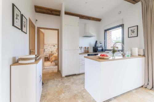 une cuisine avec des armoires blanches et un comptoir dans l'établissement Maison Melrose Lovely house near Deauville, à Cricquebœuf