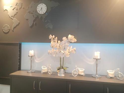 a table with a vase of flowers and clocks at Hotelik & Restauracja Amber in Raszyn