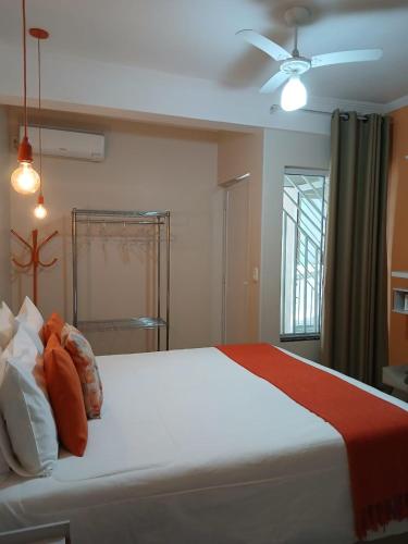 a bedroom with a large white bed with a ceiling fan at Hospedagem Quarto Chic centro Cunha in Cunha
